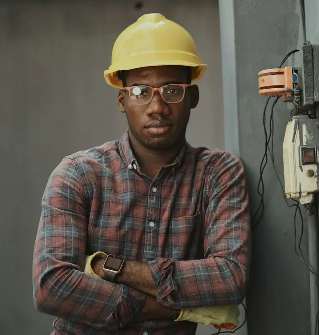 A man in a yellow hard hat and safety glasses on a building site