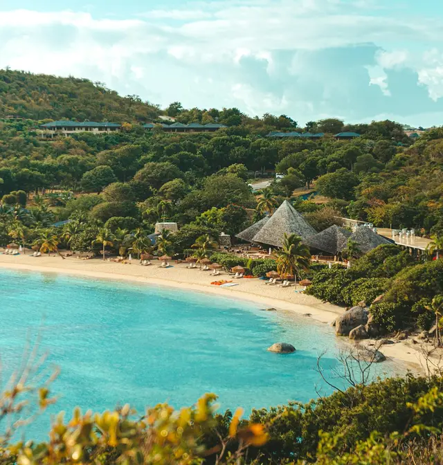 Crescent beach and thatched pavilions beside turquoise water at Little Dix Bay, British Virgin Islands