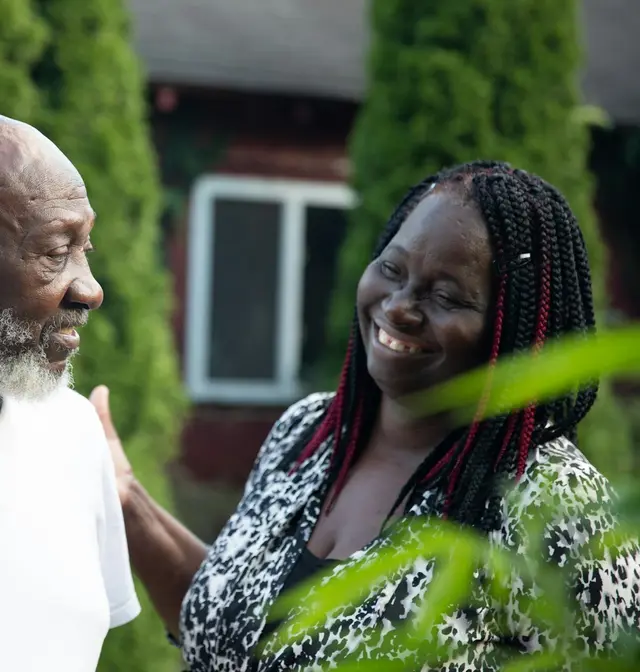 An older couple laughing together in a leafy garden